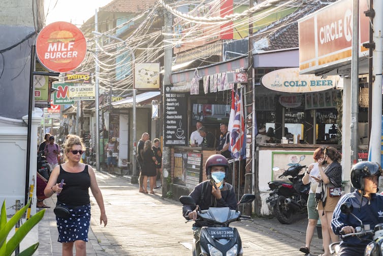 Tourists and locals hang out on a street in Bali.